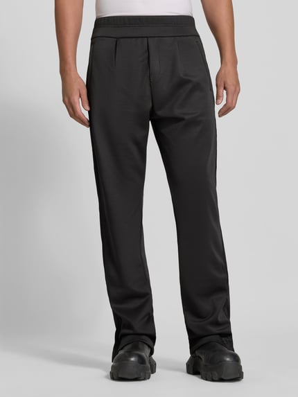 Männermodel trägt Sweatpants mit Stretch-Anteil von RHUDE in Schwarz, lockere Passform, Ziernähte, ausgestellter Beinabschluss, Nahaufnahme Oberkörper