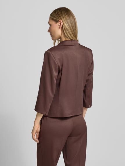 Frauenmodel trägt Slim Fit Blazer mit Reverskragen und 3/4-Arm von More & More aus Material-Mix mit Viskose-Anteil, Ganzkörperansicht Rückansicht.