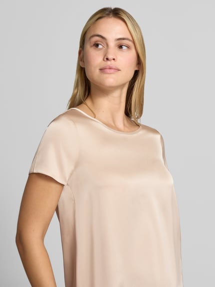 Frauenmodel trägt Bluse aus Satin mit Rundhalsausschnitt von Rinascimento, glänzender Stoff in Beige, kurzärmelig, Nahaufnahme Oberkörper. Damen Bluse von Rinascimento, Material-Mix mit Stretch-Anteil, gerade Passform, Satin, Rundhalsausschnitt, kurzärmeliges Design, rückseitiger Knopfverschluss, Rückenlänge bei Größe S: 53 cm.