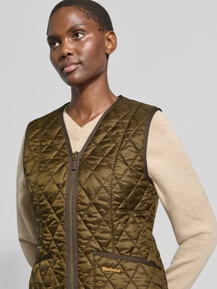 Frauenmodel trägt Regular Fit Weste mit V-Ausschnitt Modell 'BETTY' von Barbour in Olivgrün, Steppstruktur, Nahaufnahme Oberkörper, Damen Weste von Barbour