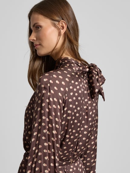 Vrouwenmodel draagt Cocktailkleid mit Stehkragen van Rinascimento, bruin met beige stippen, pure viscose, getailleerde snit, detailopname schouder en bovenrug.