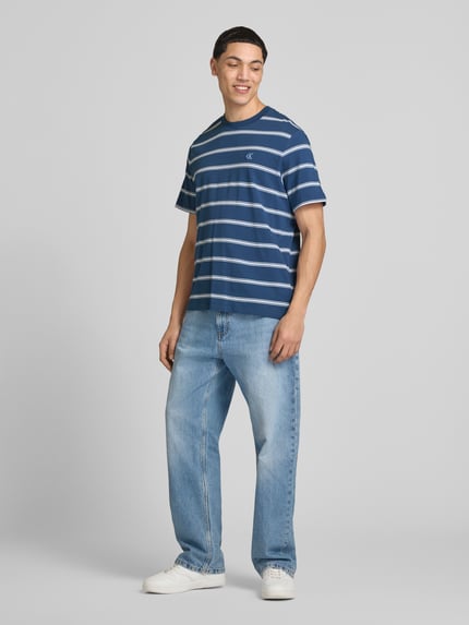 Männermodel trägt T-Shirt mit Logo-Stitching von Calvin Klein Jeans aus Reine Baumwolle, Gerader-Schnitt, Rundhalsausschnitt, Rückenlänge bei Größe M 69 cm, Ganzkörperansicht von vorne.