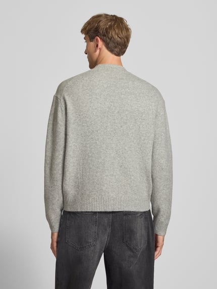 Männermodel trägt Relaxed Fit Strickpullover aus Material-Mix mit Baumwoll-Anteil von REVIEW in Hellgrau, Rückenansicht, Ganzkörperansicht Rückansicht. Rückenlänge 66 cm, Ärmellänge 61 cm, Stehkragen, elastische Abschlüsse.