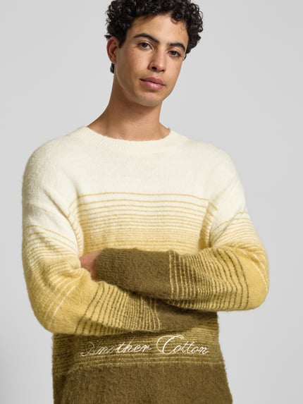 Männermodel trägt Oversized Strickpullover mit gerippten Abschlüssen von ANOTHER COTTON LAB, gestreift, Baumwoll-Mix, Nahaufnahme Oberkörper.