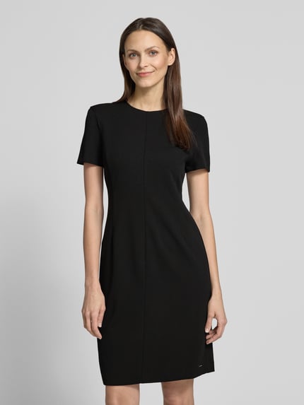 Frauenmodel trägt knielanges Etuikleid mit Rundhalsausschnitt von Calvin Klein Womenswear in Schwarz, Material-Mix mit Stretch, gerader Schnitt, Ganzkörperansicht von vorne.