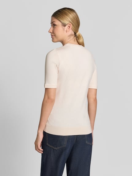 Frauenmodel trägt T-Shirt aus Viskose-Mix von Christian Berg Woman in Hellrosa, muschelförmiger gerippter Saum, Ganzkörperansicht Rückansicht.