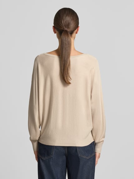 Frauenmodel trägt Strickpullover aus Viskose-Mix von COMMA in Beige mit geripptem Rundhalsausschnitt, lockerer Passform, Rückansicht, Ganzkörperansicht.