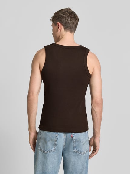 Männermodel trägt Tanktop in Ripp-Optik Modell 'Nathan' von Drykorn aus Reine Baumwolle, Slim-Fit, dunkles Braun, Rückenlänge 62 cm, Ganzkörperansicht Rückansicht.