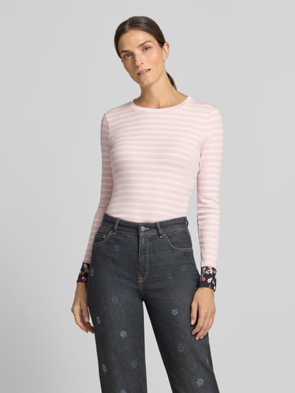 Frauenmodel trägt Slim Fit Longsleeve aus Baumwoll-Mix von Marc Cain, rosa-weiß gestreift, florale Details, Ganzkörperansicht von vorne.