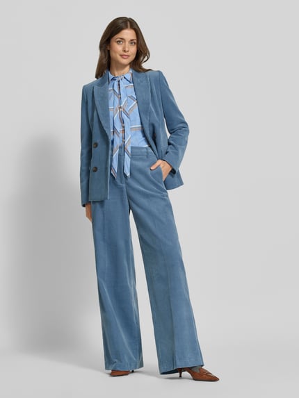 Frauenmodel trägt Regular Fit Schluppenbluse mit Brusttasche von MORE & MORE, hellblau kariert, Ganzkörperansicht von vorne.