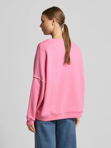 Frauenmodel trägt Oversized Sweatshirt mit Motiv-Print von miss goodlife in Pink, reine Baumwolle, gerippte Abschlüsse, Rückansicht Ganzkörper.