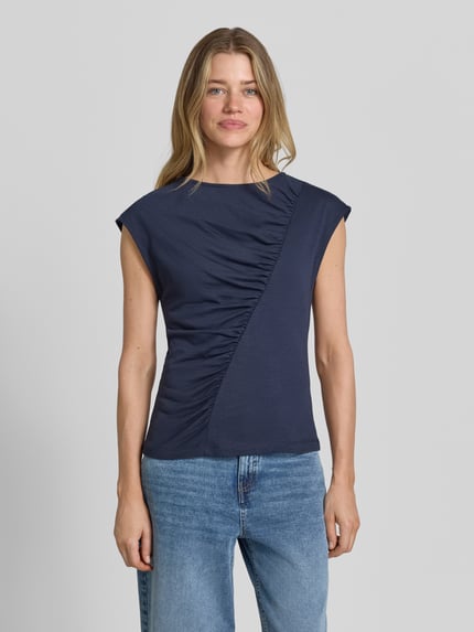 Modelka kobieca ma na sobie T-Shirt mit Rundhalsausschnitt und Drapierungen von Christian Berg Woman, damski t-shirt z mieszanki bawełny i mikromodalu, krój slim fit, okrągły dekolt, drapowania, krótkie rękawy, długość tyłu w rozmiarze S: 56 cm, kolor granatowy, gładka tekstura, widok całej sylwetki z przodu