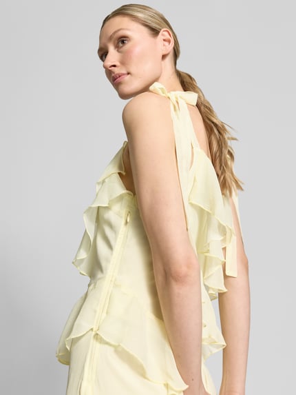 Vrouwenmodel draagt midi-jurk met volants model 'LUNA' van Vila, A-lijn, bandjes met vetersluiting, detailopname schouder.