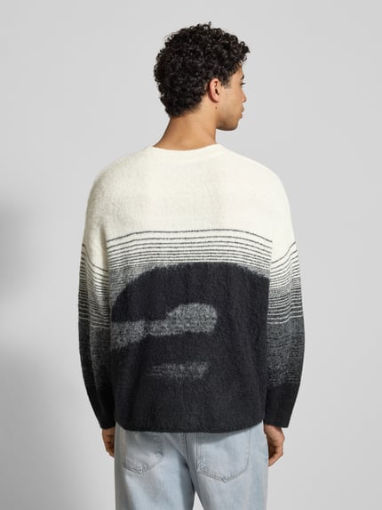 Mężczyznamodel nosi Oversized Strickpullover mit gerippten Abschlüssen von ANOTHER COTTON LAB, mieszanka materiałów z dodatkiem wełny, prążkowane wykończenia, okrągły dekolt, wyhaftowane logo, długość tyłu 68 cm, długość rękawów 55 cm, widok całej sylwetki z tyłu.