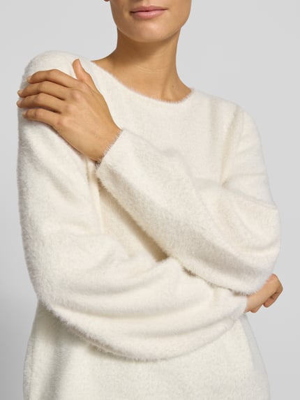 Frauenmodel trägt Strickpullover mit Rundhalsausschnitt von COMMA, cremeweiß, weiche Textur, Regular Fit, Nahaufnahme Oberkörper.