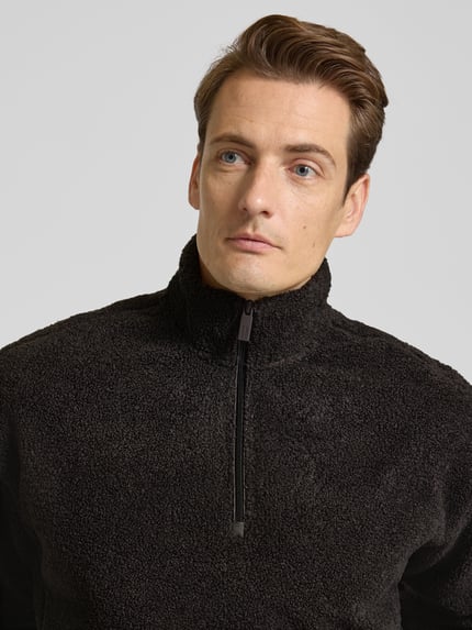 Männermodel draagt Sweatshirt mit Troyer-Kragen van JAKE*S STUDIO MEN, zwarte fleece, korte rits, losse pasvorm, Nahaufnahme Oberkörper.