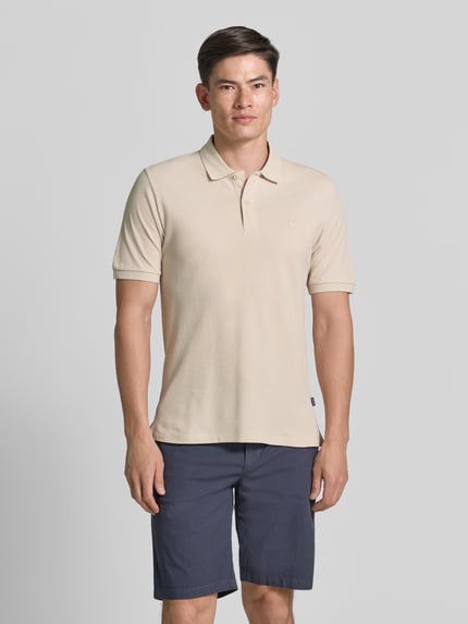 Męski model nosi Slim Fit Poloshirt mit Stitching von Jack & Jones Premium z bawełny, krój slim fit, haft, listwa guzikowa, długość tyłu w rozmiarze M: 70 cm, widok całej sylwetki z przodu.