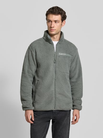 Männermodel trägt Regular Fit Fleecejacke mit Logo-Patch von Columbia in Grau, Brusttasche, Langarm, Stehkragen, Ganzkörperansicht von vorne.
