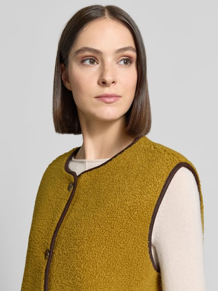 Vrouwenmodel draagt Relaxed Fit bodywarmer met doorlopende knoopsluiting van Christian Berg Woman, teddybont, ronde hals, mouwloos, zij-steekzakken, detailopname bovenlichaam.