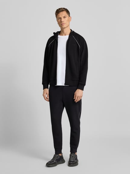 Męski model nosi Regular Fit Sweat-Anzug aus Baumwoll-Mix Modell 'TRACKSUIT SET' od BOSS Green, czarny, gładki, tkanina pikowana, pełny przód. Ganzkörperansicht von vorne.