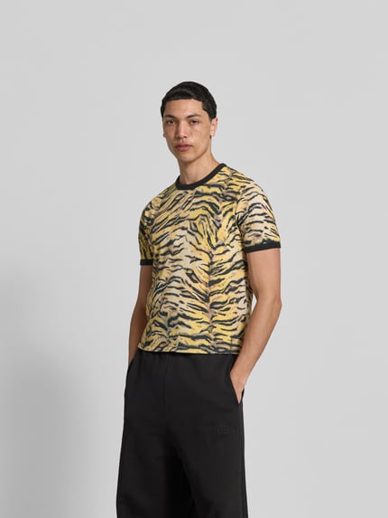 Męski model nosi T-Shirt mit Allover-Animal-Print od Kenzo z bawełny, krój slim fit, okrągły dekolt, krótki rękaw, długość tyłu 61 cm, Ganzkörperansicht von vorne.