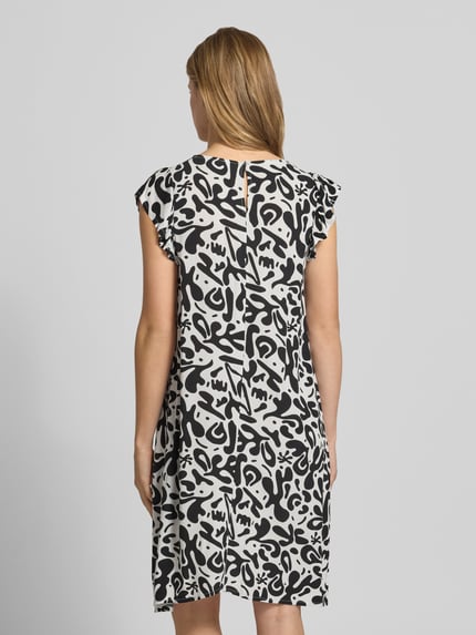 Vrouwenmodel draagt dames Regular Fit zomerjurk uit zuiver viscose model 'BARRI' van Pieces met all-over motief, knielang, ronde hals, knoop met oog, korte vlindermouwen, crêpe materiaalverwerking, rugaanzicht.