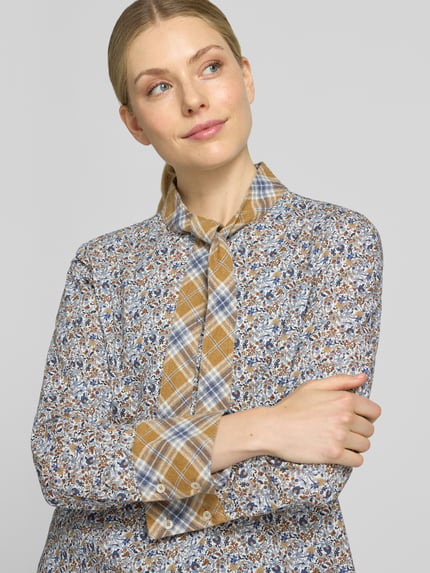Kobiece model prezentuje bluzkę z wiązaniem pod szyją 'Schluppenbluse im Allover-Look' od Emily Van den Bergh, bawełna, krój regular fit, wzór na całej powierzchni, listwa guzikowa, długość tyłu w rozmiarze 36: 63 cm, długość rękawów w rozmiarze 36: 62 cm, zbliżenie na górną część ciała.