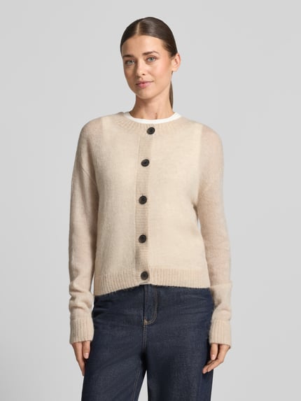 Frauenmodel trägt Strickjacke mit Woll-Anteil von COMMA in Beige, taillierte Passform, gerippte Abschlüsse, Ganzkörperansicht von vorne.