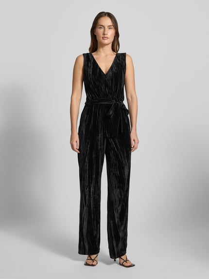 Frauenmodel trägt Regular Fit Jumpsuit aus Samt von Tom Tailor Denim in Schwarz mit V-Ausschnitt und Bindegürtel, Ganzkörperansicht von vorne.