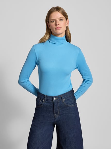 Frauenmodel trägt Slim Fit Rollkragenpullover aus Baumwoll-Mix von Marc O'Polo Denim in Unifarbe Hellblau, gerippte Abschlüsse, Ganzkörperansicht von vorne.