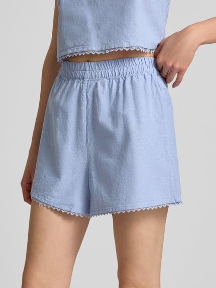 Kobiece modelka nosi Regular Fit Shorts mit Spitzenbesatz Modell 'Feoly' von American Vintage, jasnoniebieska bawełna, elastyczny pas, Szerokość w rozmiarze S: 31 cm, zbliżenie na górną część nóg