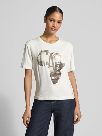 Vrouwenmodel draagt T-Shirt met Motiv-Print van monari, viscosemix met modal, regular fit, met ronde hals, print en sierstenen, voorkant bovenlichaam dichtbij.