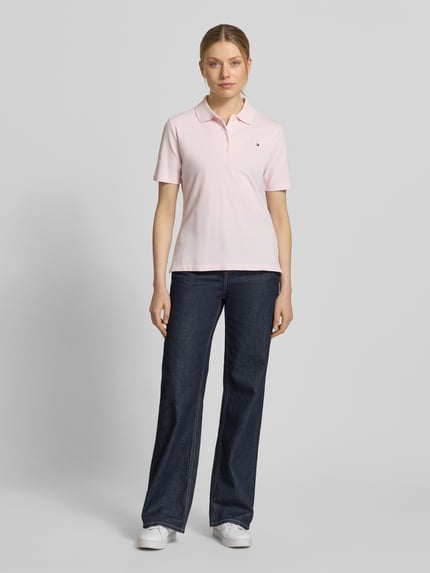 Frauenmodel trägt Regular Fit Poloshirts aus Baumwoll-Mix von Tommy Hilfiger in Hellrosa, unifarben, Piqué-Struktur, Ganzkörperansicht von vorne.