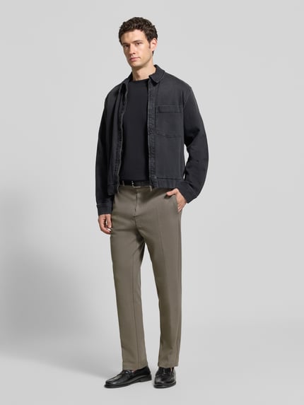 Männermodel trägt Regular Fit Sweathose aus Baumwoll-Mix von Marc O'Polo in Beige, kombiniert mit schwarzer Jacke, Ganzkörperansicht von vorne. Herren Sweathose von Marc O'Polo.