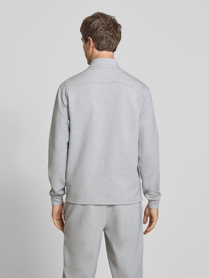 Männermodel trägt Sweatjacke mit Stehkragen und Logo von PUMA PERFORMANCE in Hellgrau, Material-Mix mit Lyocell-Anteil, Ganzkörperansicht Rückansicht.