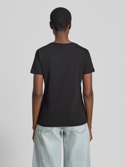 Frauenmodel trägt T-Shirt mit Ziersteinbesatz und Rundhalsausschnitt von Guess Activewear aus schwarzem Baumwoll-Elasthan-Mix, Ganzkörperansicht Rückansicht.