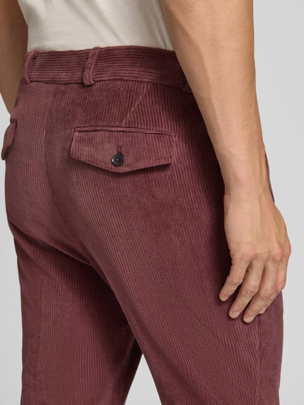 Männermodel trägt Slim Fit Hose aus Baumwoll-Mix in Cord-Optik Modell 'Cliffer' von Zuitable, rotbraune Struktur, Detailaufnahme Gesäßbereich. Elastischer Baumwoll-Mix, Eingriff- und Gesäßtaschen, Knopf- und Reißverschluss, Bundweite 37 cm, Innenbeinlänge 76 cm.