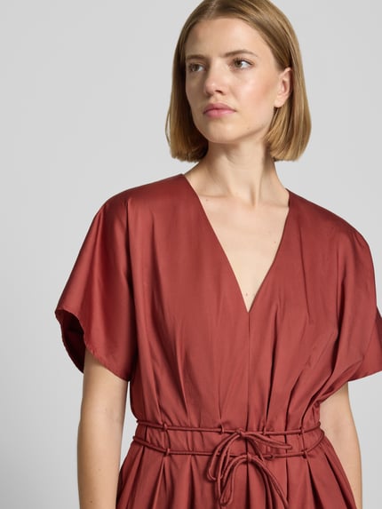 Frauenmodel trägt Cocktailkleid mit V-Ausschnitt und Schnürung von Christian Berg Cocktail, rostrot, Baumwoll-Elasthan-Mix, Nahaufnahme Oberkörper.