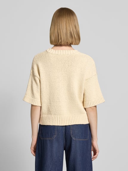 Frauenmodel trägt Regular Fit Pullover in Strick-Optik Modell 'Hannalie' von MSCH Copenhagen, Reine Baumwolle, Halbarm, V-Ausschnitt, helle Farbe, Rückenlänge 47 cm, Ärmellänge 35 cm, Strukturstrick, Ganzkörperansicht Rückansicht.