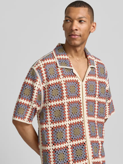 Męski model nosi Loose Fit Freizeithemd mit Kentkragen od JAKE*S STUDIO MEN, mieszanka bawełny, imitacja wykonania na szydełku, listwa guzikowa, kolorowy wzór, widok z przodu na górną część ciała. Długość tyłu w rozmiarze M: 75 cm, szerokość ramion w rozmiarze M: 63 cm, długość rękawów w rozmiarze M: 27 cm.