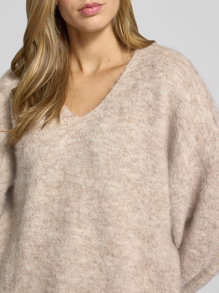 Frauenmodel trägt Pullover mit V-Ausschnitt Modell 'PCALLIE' von PIECES, melierte Optik, Strick, Langarm, Nahaufnahme Oberkörper.
