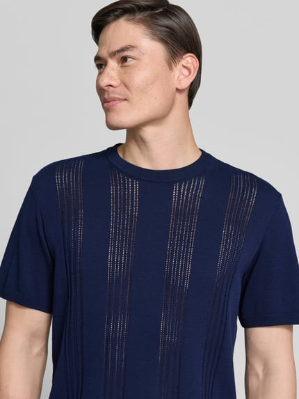 Männermodel trägt Relaxed Fit T-Shirt aus reiner Baumwolle von Armedangels in Optik: Unifarben, Feinstrick, Label-Patch, Nahaufnahme Oberkörper.