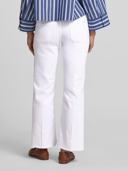 Frauenmodel trägt Relaxed Fit Jeans aus Baumwoll-Mix Modell 'TESS' von Cambio in weißer Denim-Optik mit Fransen Beinabschluss, Gesäßtaschen, Logo-Applikation, Label-Patch, Gürtelschlaufen, Knopf und verdecktem Reißverschluss, Twill-Materialverarbeitung, Ankle-Länge, Ganzkörperansicht Rückansicht.