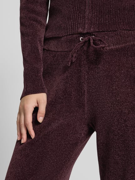 Frauenmodel trägt Sweathose mit Tunnelzug von Juicy Couture in unifarbener Optik mit Kordeln und elastischem Bund, Nahaufnahme Oberkörper.
