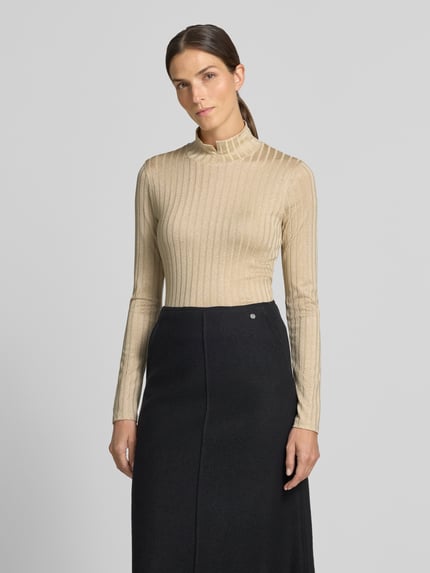Frauenmodel trägt Longsleeve mit Rollkragen von Marc Cain in Beige mit Ripp-Struktur und Glitzer-Garn, Ganzkörperansicht von vorne.