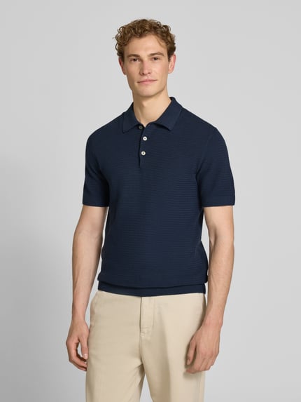Männermodel trägt Regular Fit Poloshirt mit Strukturmuster Modell 'Riley' von Jack & Jones Premium in Dunkelblau, reine Baumwolle, Kurzarm, Ganzkörperansicht von vorne.