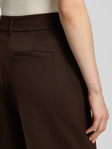 Frauenmodel trägt Weite Hose mit Viskose-Anteil von s.Oliver RED LABEL in Dunkelbraun mit strukturierter Oberfläche, Nahaufnahme Rückansicht.