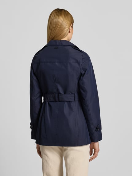 Frauenmodel trägt Regular Fit Trenchcoat aus Baumwoll-Mix von s.Oliver RED LABEL in Dunkelblau, klare Linien, glatte Twill-Struktur, Ganzkörperansicht Rückansicht.