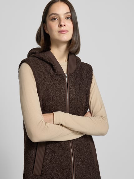 Frauenmodel trägt Regular Fit Weste mit Kapuze von Tom Tailor in Dunkelbraun mit strukturierter Oberfläche und Reißverschluss, Nahaufnahme Oberkörper, Damen Weste von Tom Tailor.