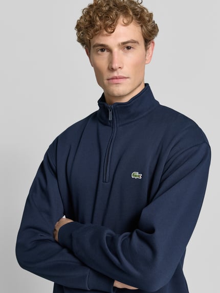 Männermodel trägt dunkelblauen Regular Fit Troyer aus Baumwoll-Mix von Lacoste, dezentes Logo, Nahaufnahme Oberkörper, Herren Troyer von Lacoste.